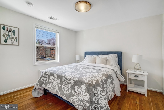 bedroom with visible vents, baseboards, and wood finished floors