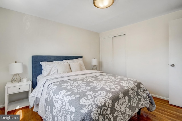 bedroom with wood finished floors, a closet, and baseboards