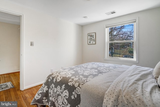 bedroom with hardwood / wood-style floors, baseboards, and visible vents