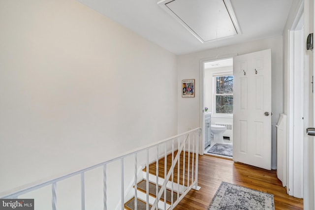 corridor featuring an upstairs landing, attic access, and wood finished floors