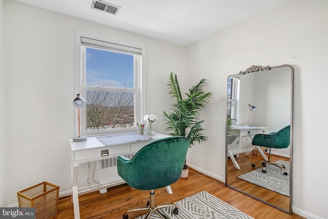 office area featuring visible vents, baseboards, and wood finished floors