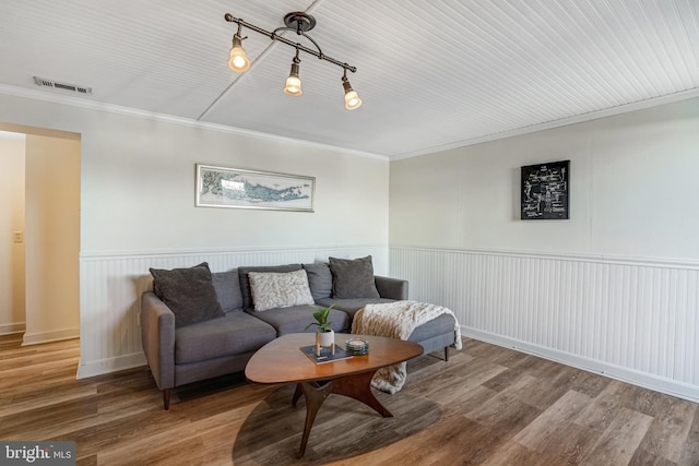 living area with crown molding, wood finished floors, visible vents, and wainscoting