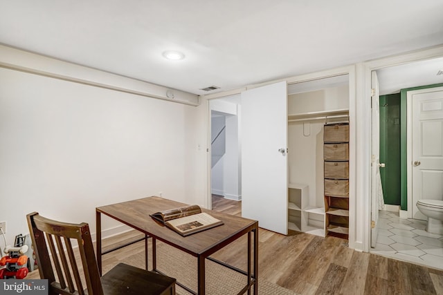 home office with visible vents, light wood-style flooring, and baseboards