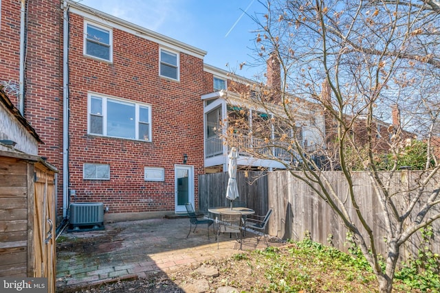 back of house with brick siding, central AC unit, a patio, and fence