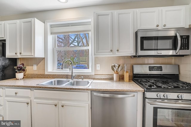 kitchen featuring decorative backsplash, white cabinets, appliances with stainless steel finishes, and a sink