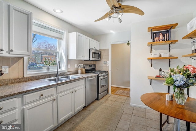 kitchen with light tile patterned floors, open shelves, a sink, stainless steel appliances, and tasteful backsplash