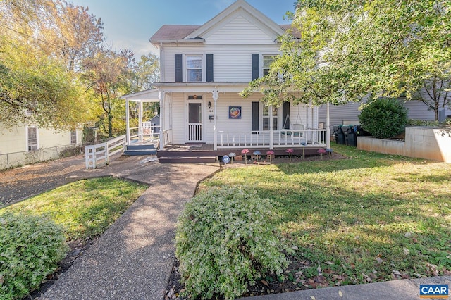 view of front of home featuring covered porch, fence, and a front lawn