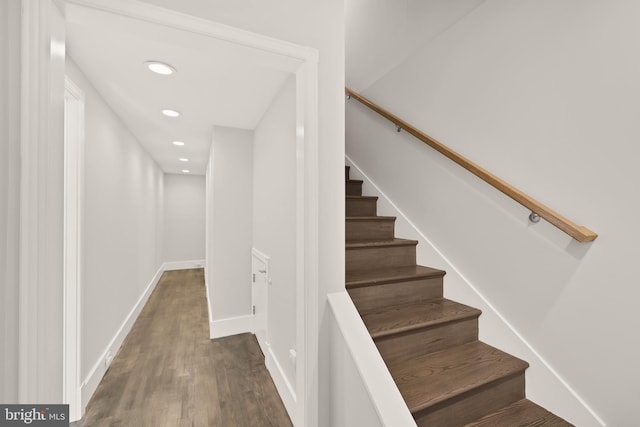 staircase featuring baseboards, wood finished floors, and recessed lighting