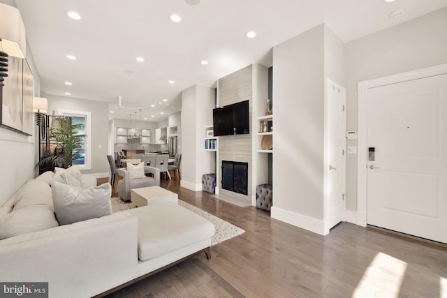 living area featuring baseboards, a large fireplace, wood finished floors, and recessed lighting