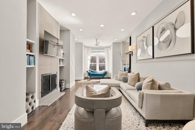 living room featuring a fireplace, baseboards, wood finished floors, and recessed lighting