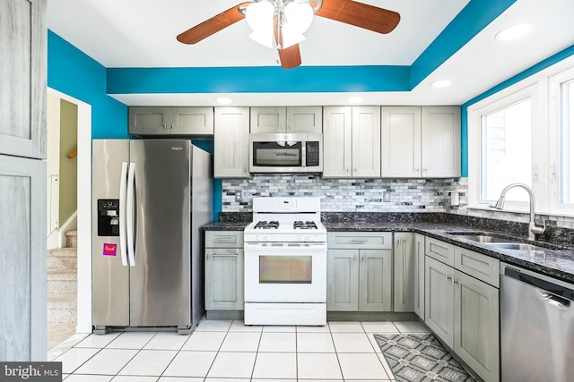 kitchen with light tile patterned floors, appliances with stainless steel finishes, backsplash, and a sink