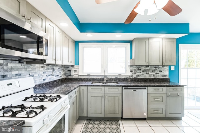 kitchen featuring stainless steel appliances, a sink, backsplash, and light tile patterned floors