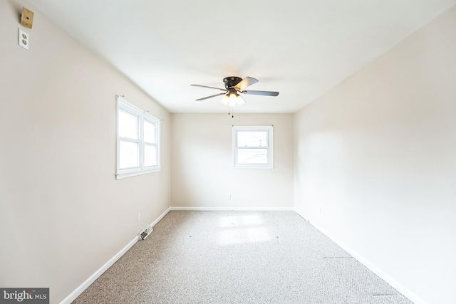 empty room featuring ceiling fan, visible vents, and baseboards