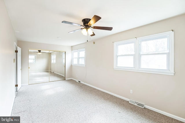 unfurnished bedroom featuring ceiling fan, carpet flooring, visible vents, baseboards, and a closet