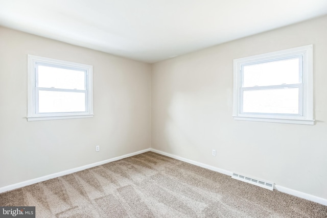 carpeted empty room featuring visible vents and baseboards