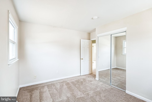 unfurnished bedroom with carpet floors, baseboards, and a closet