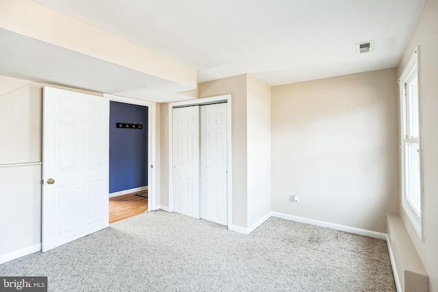 unfurnished bedroom featuring carpet, a closet, visible vents, and baseboards