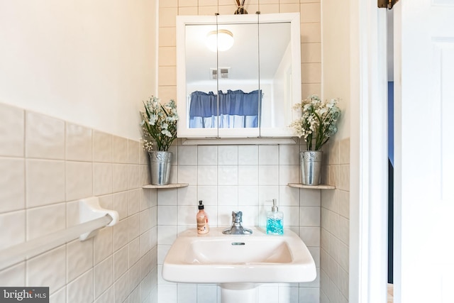 bathroom with tile walls, visible vents, and a sink