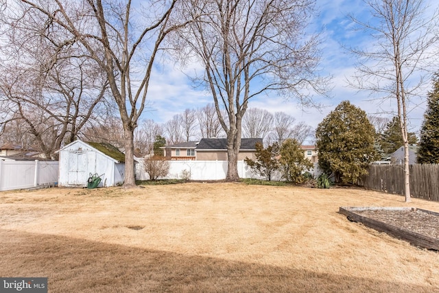 view of yard with a fenced backyard, a storage unit, and an outbuilding