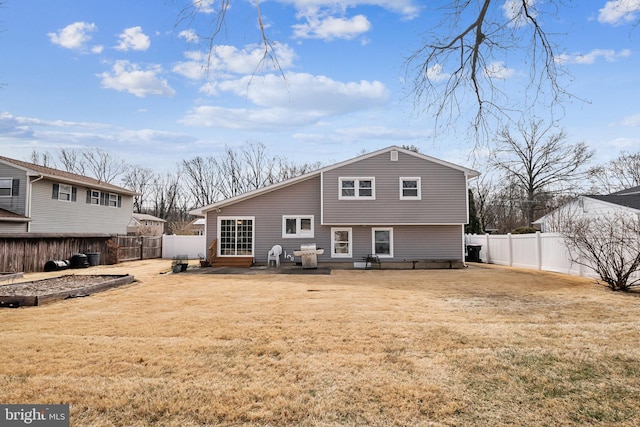 rear view of house with a fenced backyard and a lawn