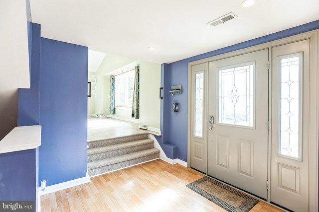 foyer entrance featuring a wealth of natural light, visible vents, and wood finished floors