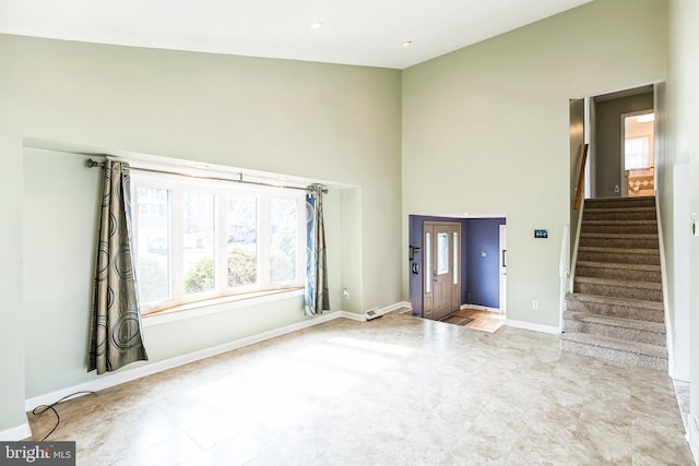 interior space featuring stairs, a high ceiling, and baseboards