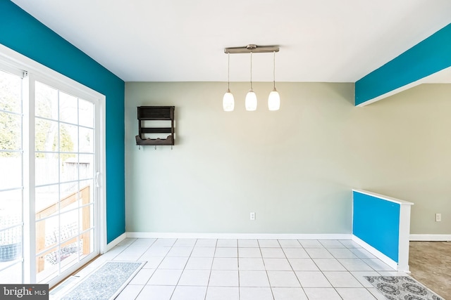 unfurnished dining area with light tile patterned floors, baseboards, and vaulted ceiling