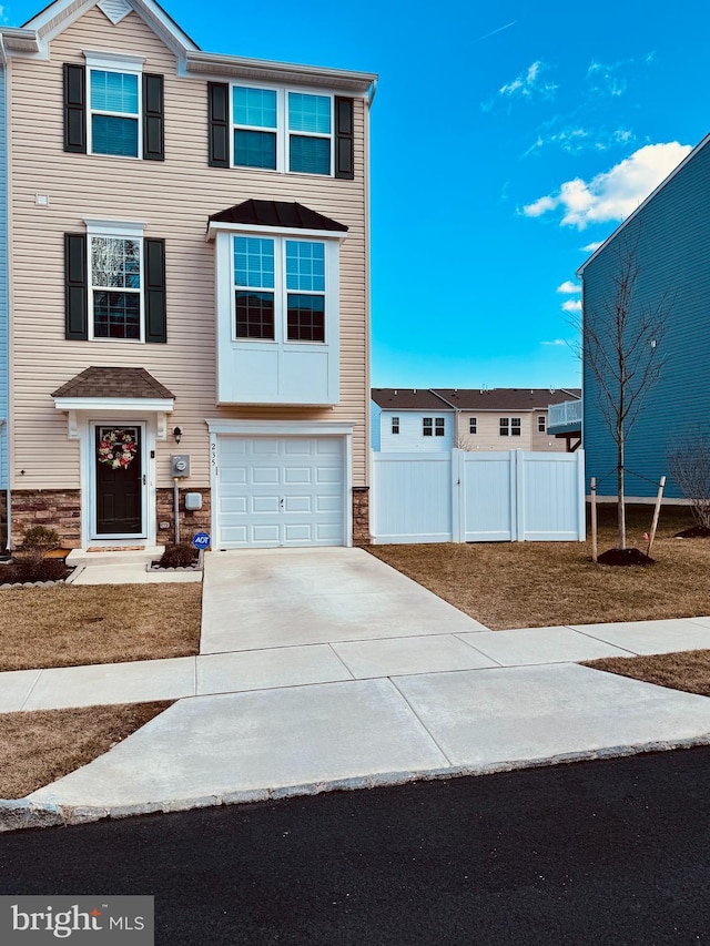 view of front of house with a garage, concrete driveway, and fence