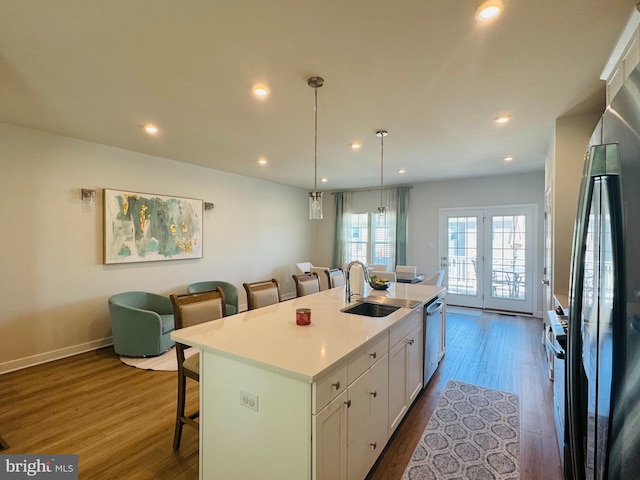 kitchen with white cabinets, dark wood finished floors, a kitchen breakfast bar, freestanding refrigerator, and a sink