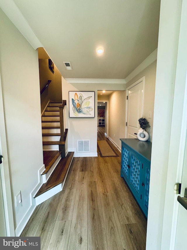 hall with baseboards, visible vents, stairway, and wood finished floors