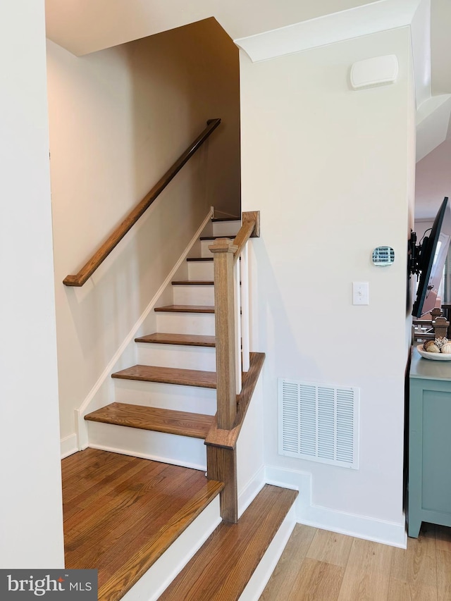 stairs featuring visible vents, baseboards, and wood finished floors