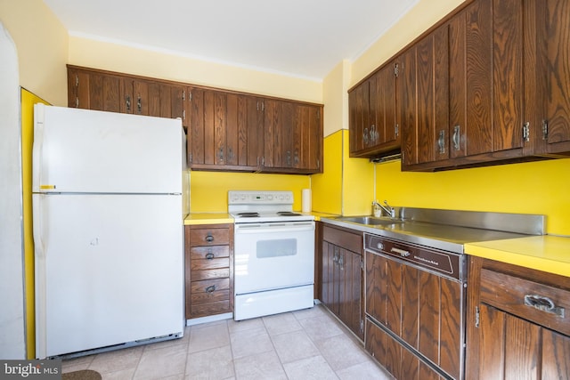 kitchen featuring white appliances, light tile patterned floors, ornamental molding, a sink, and light countertops