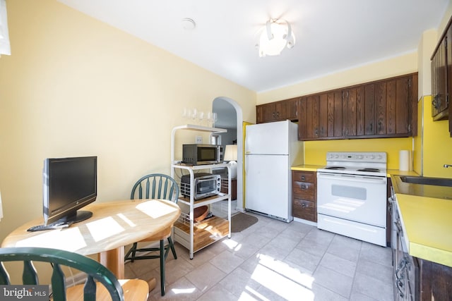 kitchen featuring white appliances, light tile patterned floors, light countertops, and dark brown cabinetry