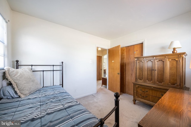 bedroom featuring a closet, light carpet, and baseboards