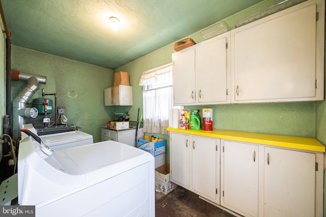 washroom featuring cabinet space, a textured wall, and separate washer and dryer