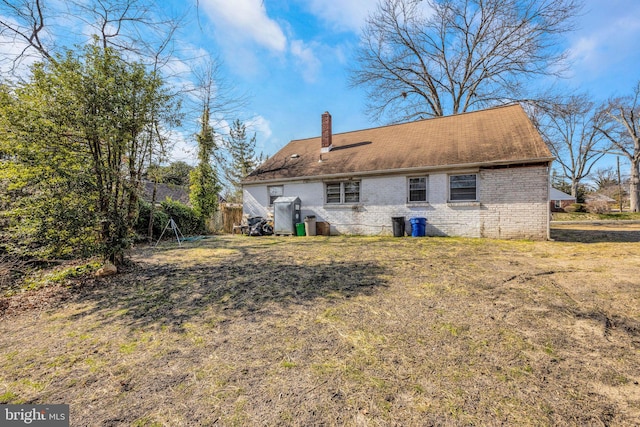 back of property with a yard, brick siding, and a chimney