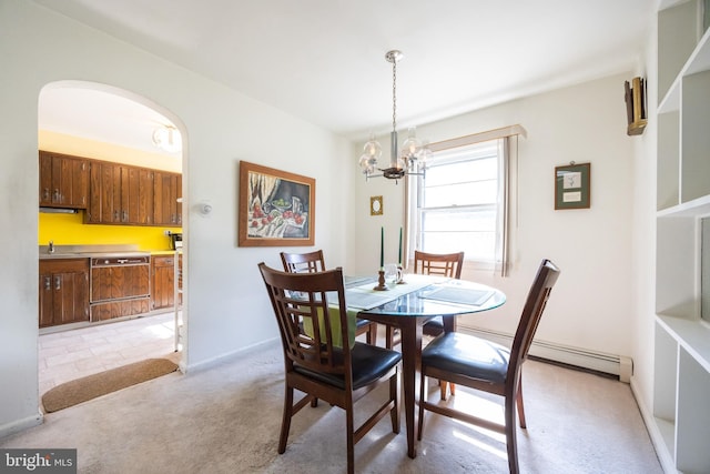 dining room featuring light carpet, a notable chandelier, arched walkways, and baseboards