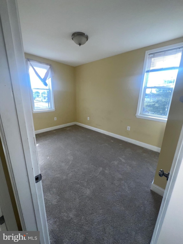 carpeted empty room featuring baseboards