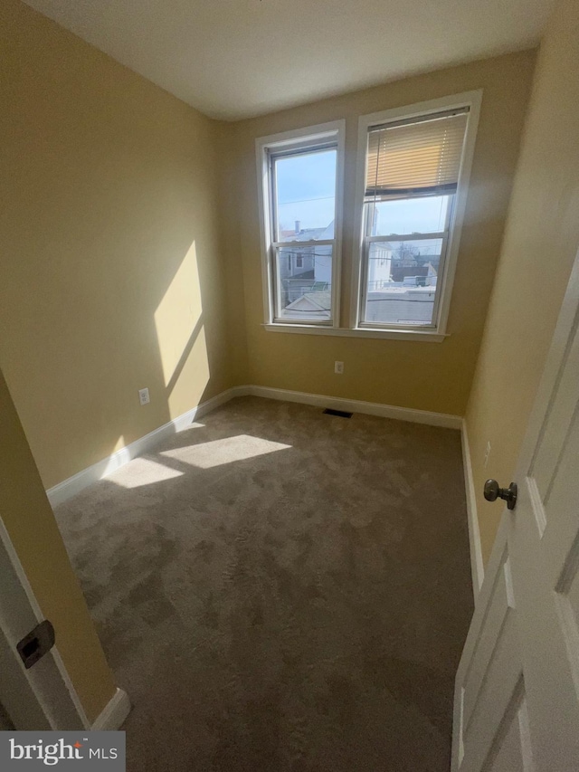 carpeted empty room featuring baseboards and visible vents