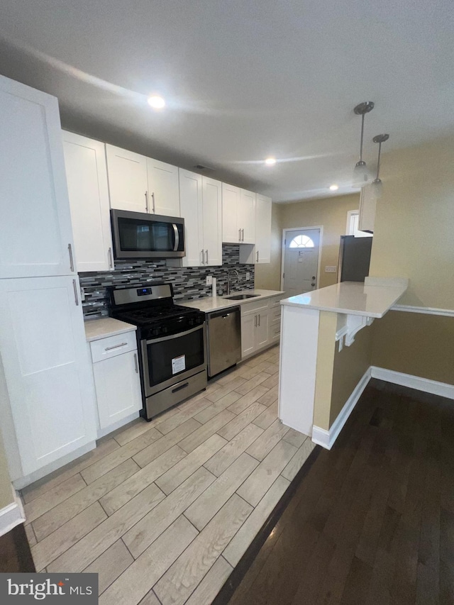 kitchen with stainless steel appliances, light countertops, light wood-style flooring, backsplash, and white cabinets