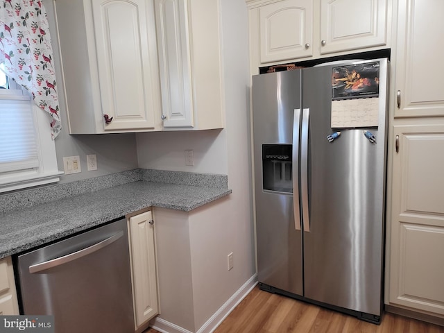 kitchen featuring appliances with stainless steel finishes, light wood-type flooring, white cabinets, and baseboards