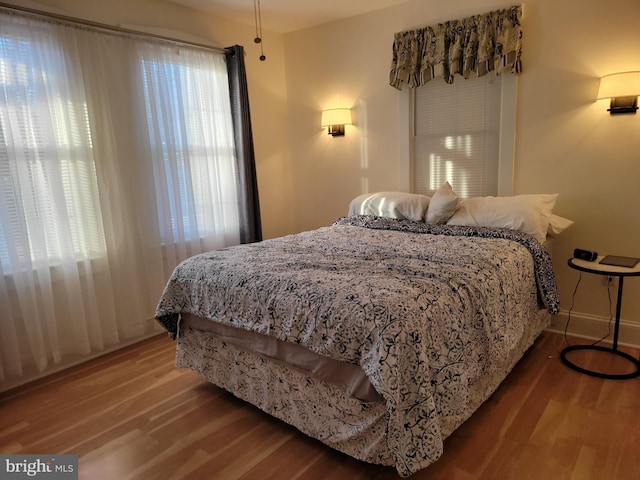 bedroom featuring multiple windows, baseboards, and wood finished floors