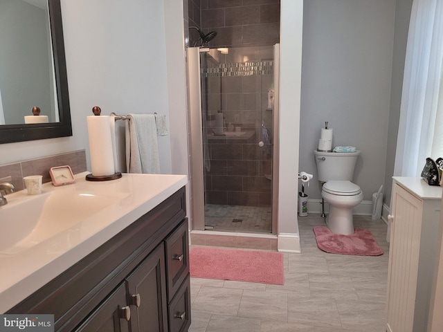 bathroom with toilet, a stall shower, baseboards, and vanity