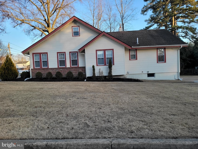 view of front of property featuring brick siding, a chimney, a front yard, and a shingled roof