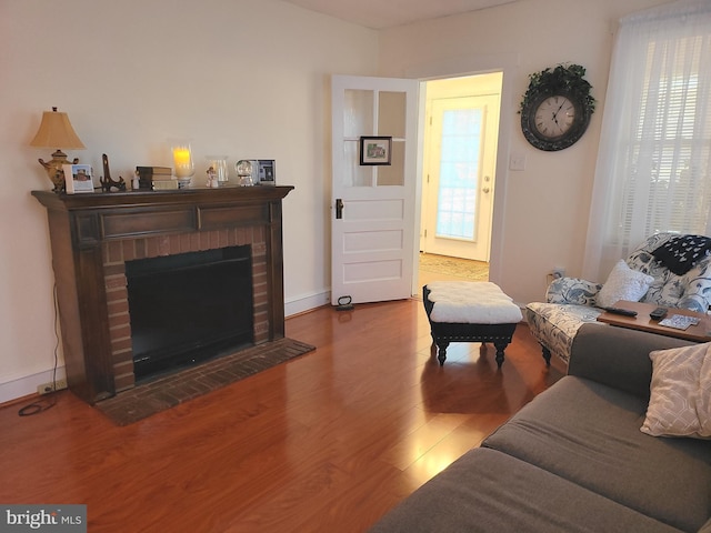 living area featuring a brick fireplace, wood finished floors, and baseboards