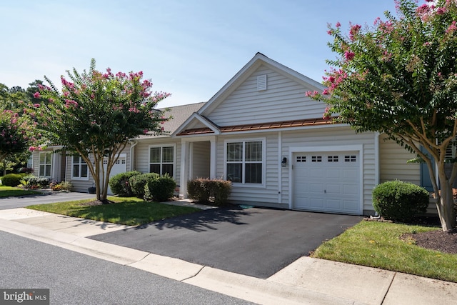 view of front of property featuring metal roof, aphalt driveway, a standing seam roof, and an attached garage