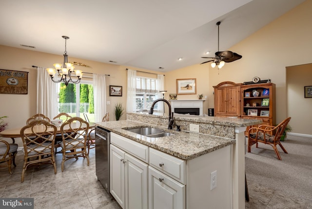 kitchen featuring a fireplace, a sink, visible vents, stainless steel dishwasher, and a center island with sink