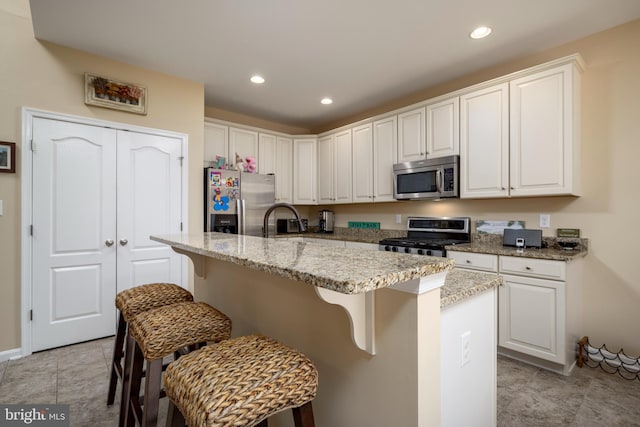 kitchen featuring stainless steel appliances, an island with sink, and white cabinetry