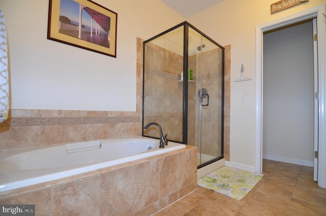 bathroom with a stall shower, a bath, and baseboards