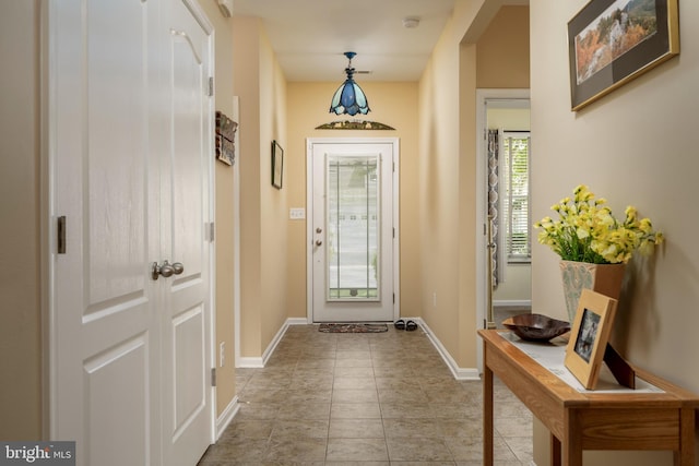 doorway to outside with baseboards and light tile patterned floors